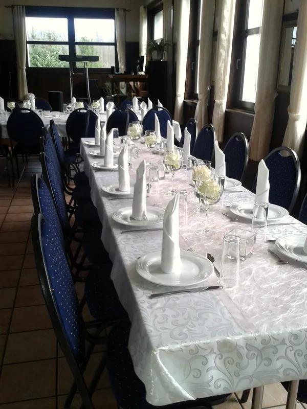 Festive table with white tableware, wine glasses and blue banquet chairs