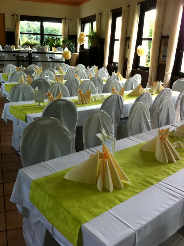 Long tables with green runners, cream napkins and paper flowers