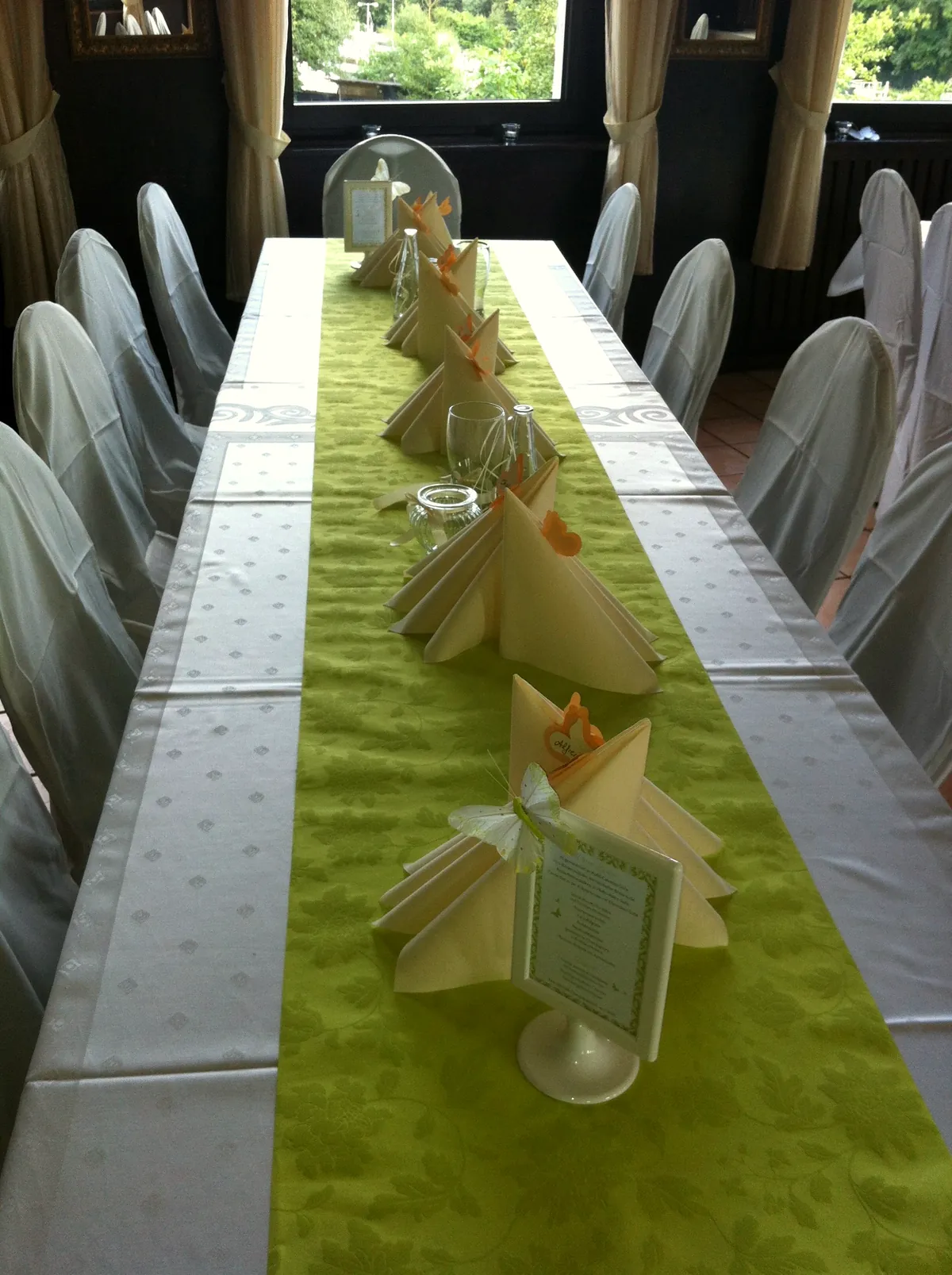 Long table with green runner, folded napkins and a menu card